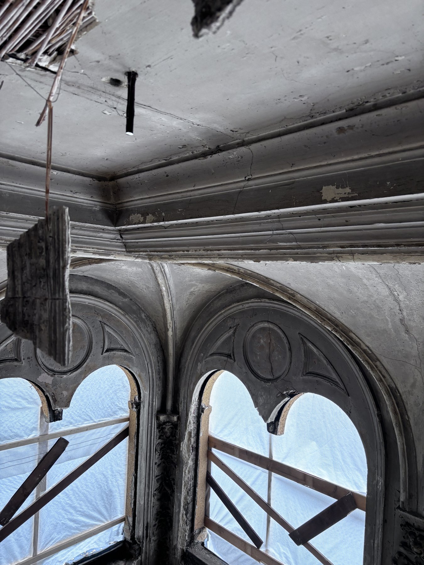 Spitzbogenfenster eines historischen Saals während der Sanierung, mit Holzabstützungen im Gerüst